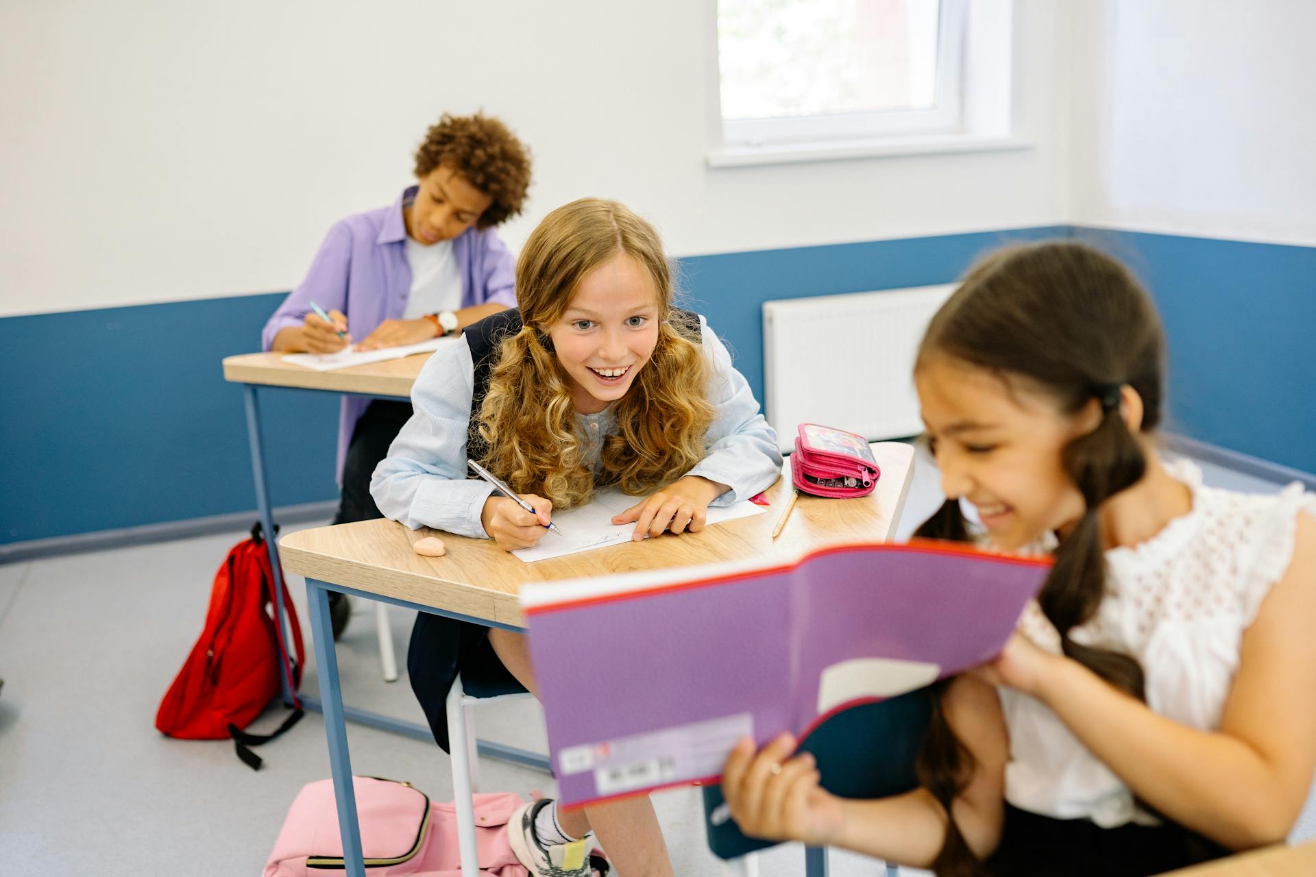 Children smiling and working at their desks in a classroom