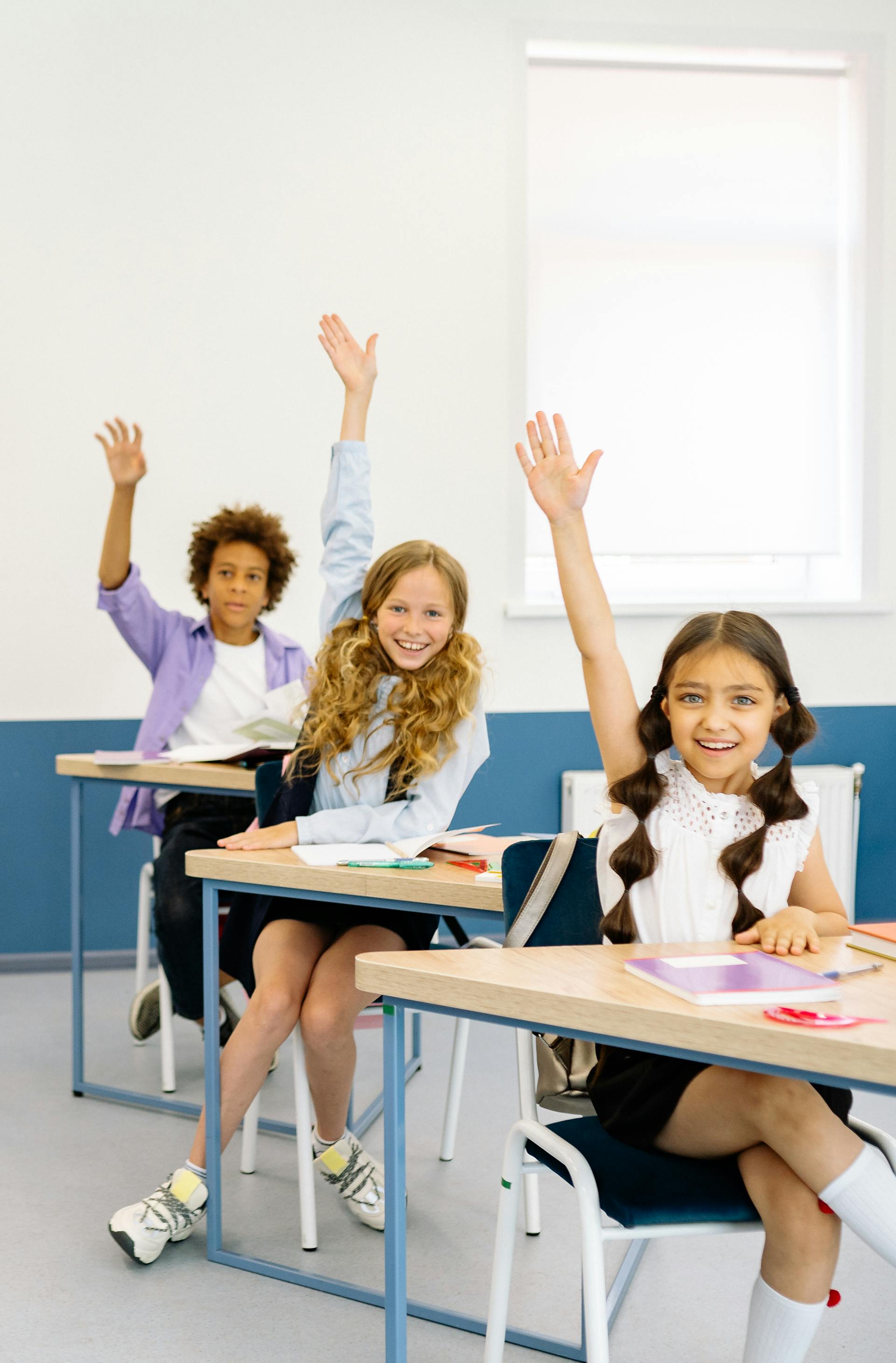 A classroom full of enthusiastic children raising their hands