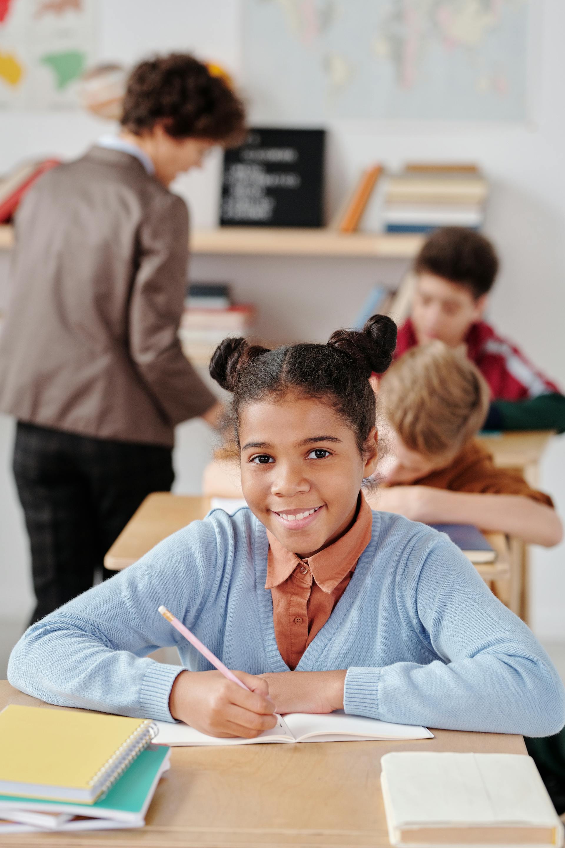 A smiling student writing at her desk in a classroom